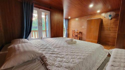 a bedroom with a large white bed with a window at Green Bamboo Lodge Resort in Cat Tien