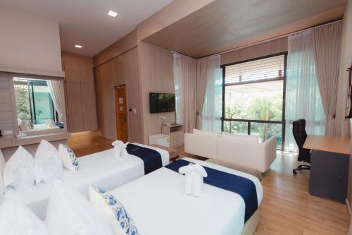 a hotel room with two beds and a desk at Treescape Resort Chiangmai in Chiang Mai