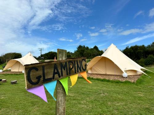 a sign that reads swinging in front of tents at Lakeside Glamping Firecrest in Saint Columb Major