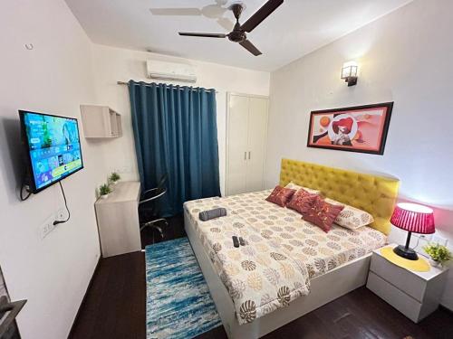 Un dormitorio con una cama y un televisor. en Maize - Aashray, en Noida