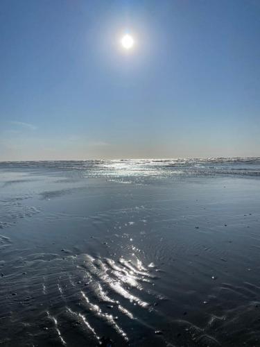 a beach with the sun shining on the water at Residentie Marie-Julie in Middelkerke