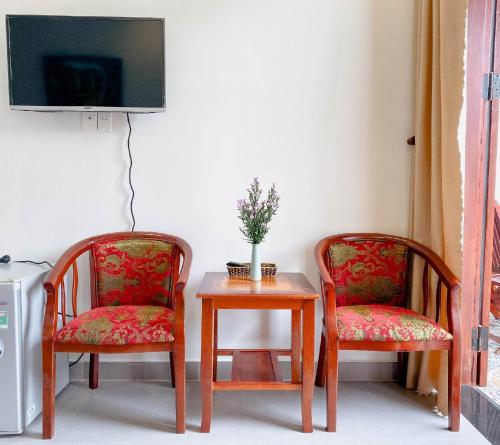two chairs and a table with a tv on a wall at Nhà Bống Villa in Hoi An