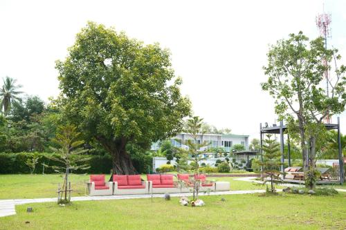 a couch sitting in a park with a tree at Socool Grand Hotel in Nang Rong