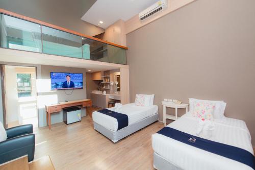 a hotel room with two beds and a tv at Treescape Resort Chiangmai in Chiang Mai