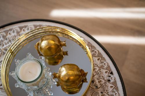 a glass table with a plate with gold skulls and a candle at Lazuli Hermes Apartments in Larnaka