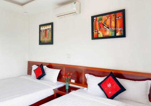 two beds in a room with white and red pillows at Nhà Bống Villa in Hoi An