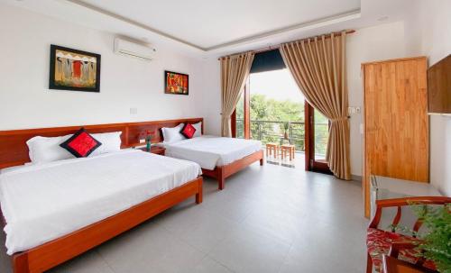 a hotel room with two beds and a balcony at Nhà Bống Villa in Hoi An
