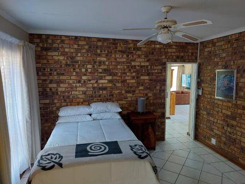 a bedroom with a bed and a brick wall at The Green Lizard Self-catering House in Nelspruit