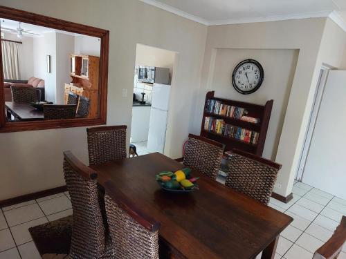 a dining room with a table and a clock on the wall at The Green Lizard Self-catering House in Nelspruit
