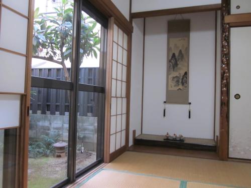 an empty room with glass doors and a tree at Enman Guest House Osaka in Osaka