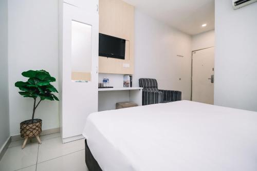 ein Schlafzimmer mit einem weißen Bett und einer Pflanze in der Unterkunft Swing & Pillows - Subang SS15 in Subang Jaya