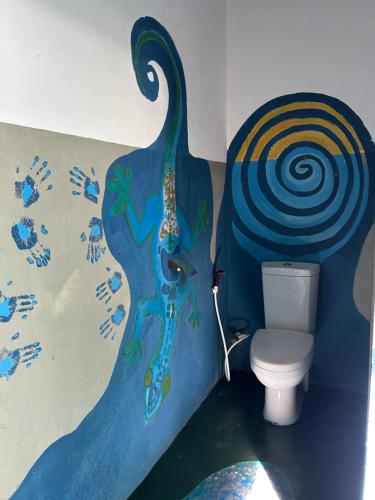 a bathroom with a toilet with a peacock painted on the wall at STARFISH beach bungalow in Arugam Bay