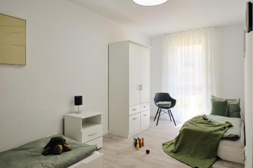 a white bedroom with a bed and a chair at Apartment B 1 "Pine Hill Resort" Family mit eigenem Fahrradabteil und Südterrasse im "Pine Hill Resort" in Zirchow