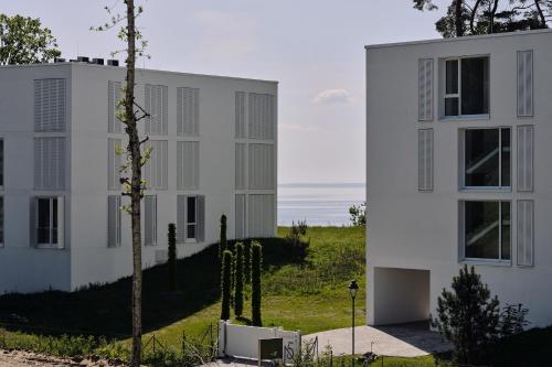 a white building with a tree in front of it at Apartment B 1 "Pine Hill Resort" Familienfreundlich mit eigenem Fahrradabteil & eingeschränktem Haffblick in Zirchow