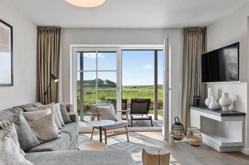 a living room with a couch and a table and chairs at Alte Schule Westerhever Welt in Westerhever