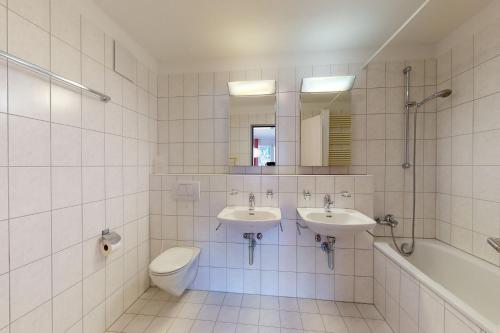 a bathroom with two sinks and a toilet and a tub at Apartment Crappun 3 in Samedan