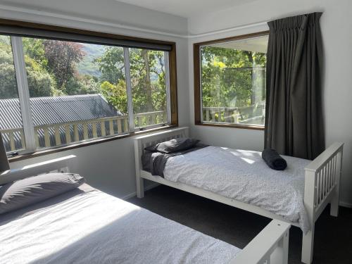 two beds in a room with two windows at Wanaka Lake walk 2 town, Lake & Mount View, townhouse in Wanaka
