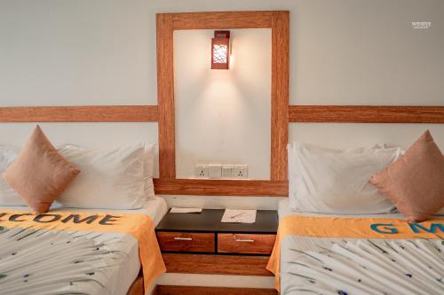 Dos camas en una habitación con espejo. en G.M.T.SORABORA VILLAGE HOTEL, en Mahiyangana