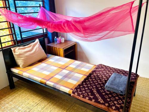 a bedroom with a bed with a pink mosquito net at Manel Guesthouse and Restaurant in Sen Monorom