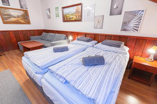 two beds in a small room with a couch at Penzión Grand, Self Check-In, free private parking in Banská Bystrica