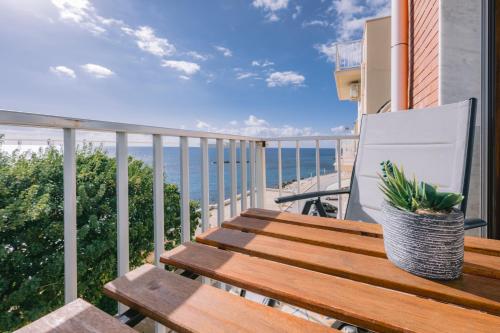 a wooden bench on a balcony with a view of the ocean at Mare Azzurro Appartamento in Sciacca