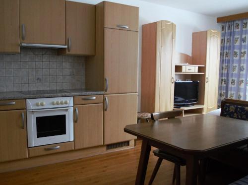 kuchnia z drewnianymi szafkami, stołem i telewizorem w obiekcie Appartment Danterhof w Mayrhofen
