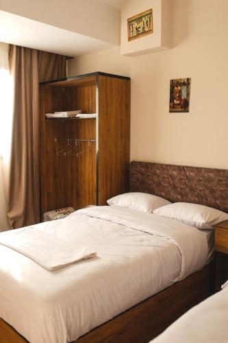 a bedroom with two beds and a wooden cabinet at The View Pyramids Gold one in Cairo