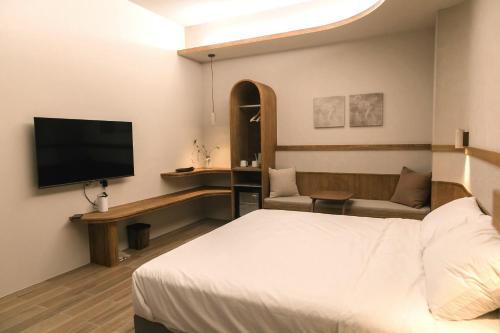 a hotel room with a bed and a flat screen tv at Yuzhi Wenlv B&B in Hualien City