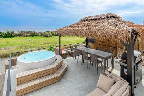 a patio with a hot tub and a table and chairs at The BONDS SPAオーシャンプライベートヴィラー千葉白浜ー in Minamiboso