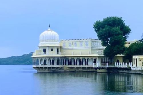 a large building in the middle of the water at Phool Mahal Palace in Kishangarh