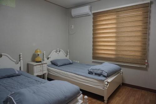 zwei Einzelbetten in einem Zimmer mit Fenster in der Unterkunft tebaz in Jeju-do