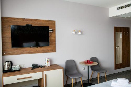 a room with two chairs and a television on a wall at BG Hotel in Sofia