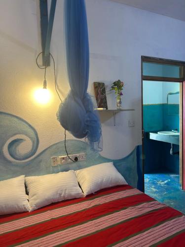 a bedroom with a bed with a painting on the wall at STARFISH beach bungalow in Arugam Bay
