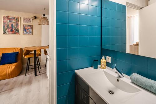 La salle de bains est pourvue d'un lavabo et de carrelage bleu. dans l'établissement Studio Soleil d'Azur, à Narbonne
