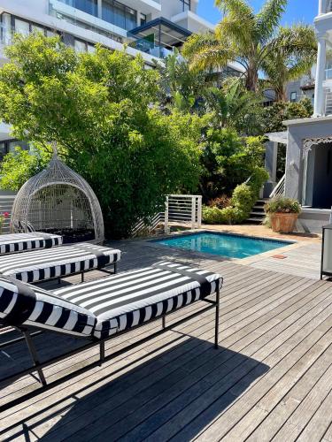 a couple of lounge chairs sitting next to a swimming pool at Romney Park Luxury Apartments by The Stay Collection in Cape Town