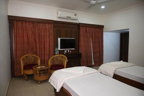 a hotel room with two beds and a flat screen tv at Santiniketan Residency in Shānti Niketan