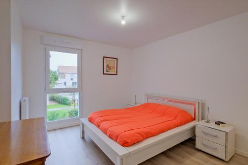 - une chambre avec un lit doté d'un couvre-lit orange et d'une fenêtre dans l'établissement L'Escapade pornicaise - Joli appt à Pornic, à Pornic