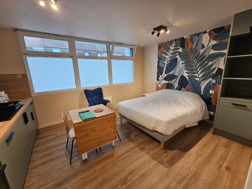 a bedroom with a bed and a table and a chair at Les Gîtes du Moulin des Loups in Saint-Amand-les-Eaux
