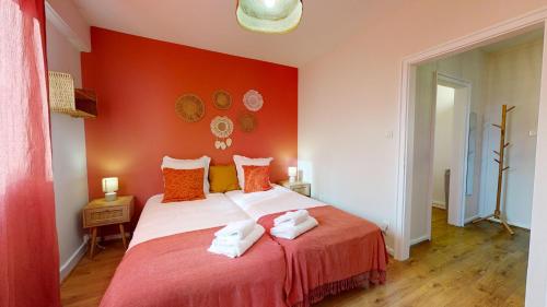 - une chambre rouge avec un lit et des serviettes dans l'établissement Chez Léa 1 Parking, à Colmar