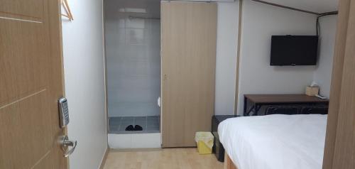 a bedroom with a bed and a shower and a television at Stayin Myeongdong Guesthouse - Foreigners only in Seoul