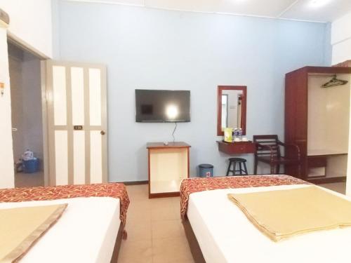 a room with two beds and a tv on the wall at Analisa Beach Resort in Pangkor