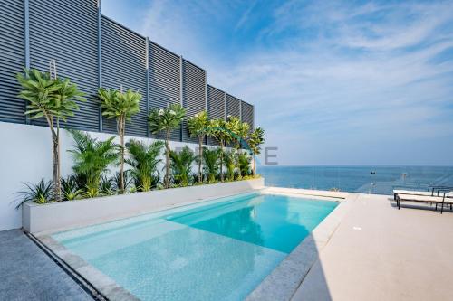 a swimming pool on the side of a building with palm trees at Elegant 4BR Villa with Assistant Room in Al Dana Island, Sharm, Fujairah by Deluxe Holiday Homes in Fujairah