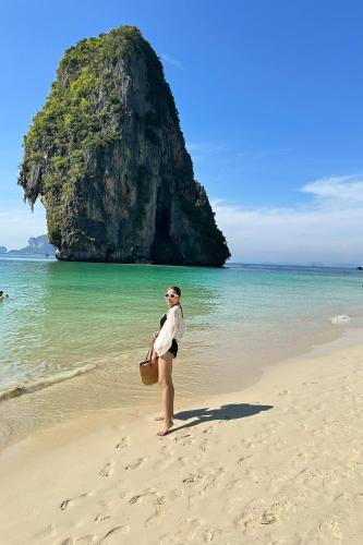 a woman standing on a beach near the ocean at M.P Resort in Ao Nam Mao