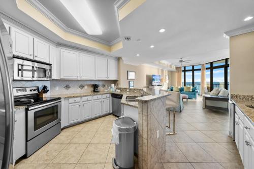 a large kitchen with white cabinets and a living room at Oasis at Orange Beach 1102 in Orange Beach