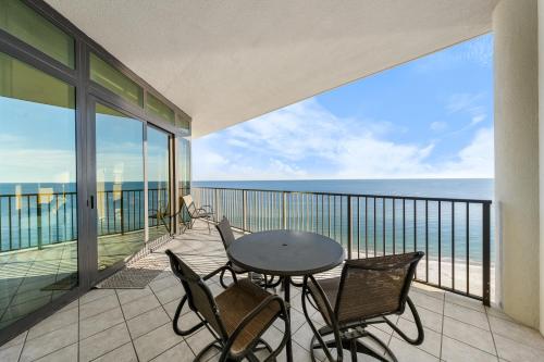 a balcony with a table and chairs and the ocean at Oasis at Orange Beach 1102 in Orange Beach