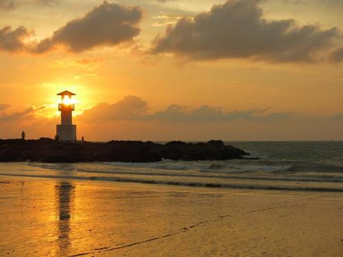 a lighthouse on the beach with the sunset in the background at Happy Lagoon Bungalow in Khao Lak