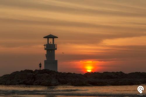 a lighthouse on the beach with the sunset in the background at Happy Lagoon Bungalow in Khao Lak