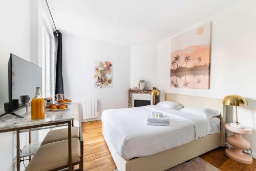 une chambre avec un lit et un bureau avec une télévision dans l'établissement Studio neuf Metro Jaures- Paris 19 - 2P - FLAT-GUEST, à Paris