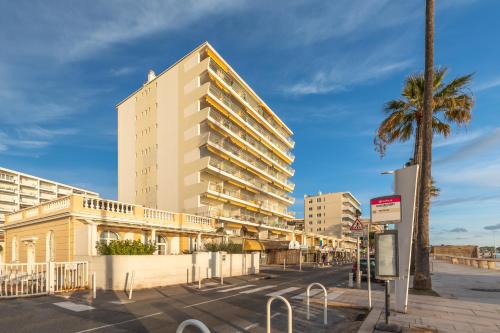 un grand bâtiment dans une rue avec un palmier dans l'établissement Le Soleil Front de Mer Centre Juan Les Pins, à Antibes