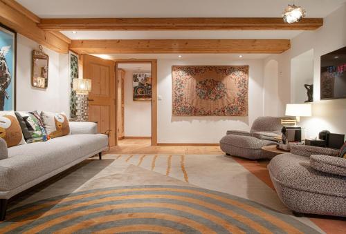 a living room with two couches and a rug at Hotel Olden in Gstaad
